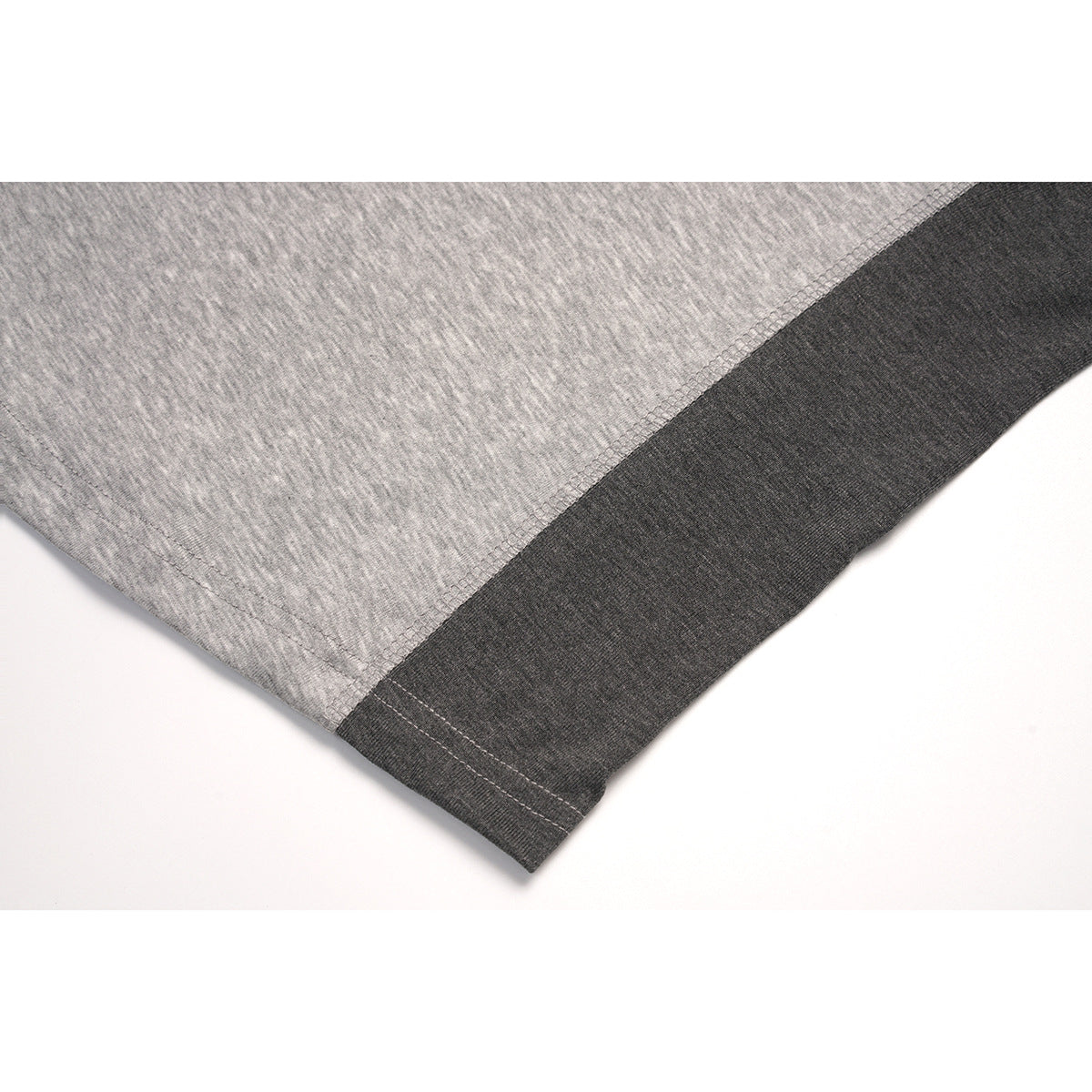 Close-up of the heather-gray top's hem with a wide charcoal contrast panel and visible stitching.