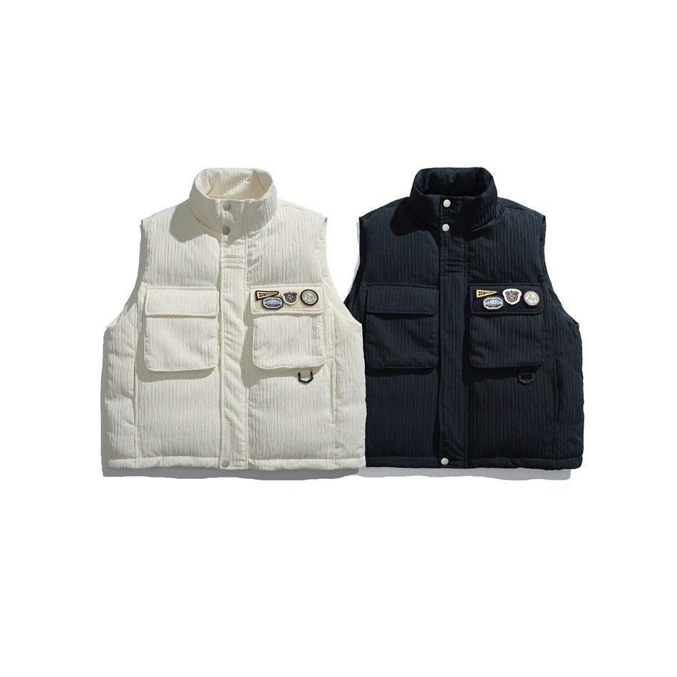 Front views of the same utility vest in ivory and dark navy, each with large pockets and decorative patches.