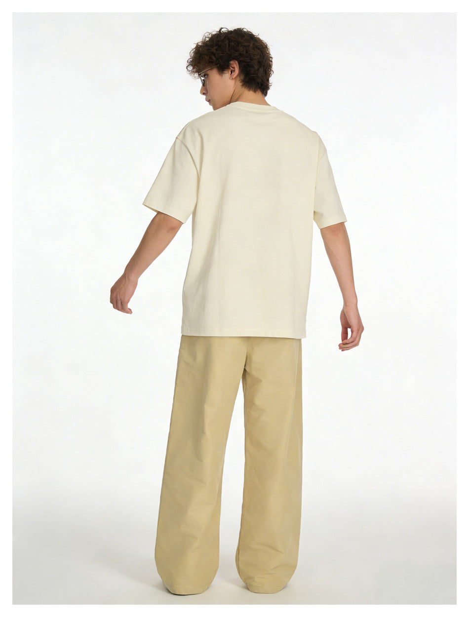 Rear view of a model wearing an off-white oversized T-shirt and light beige wide-leg pants.