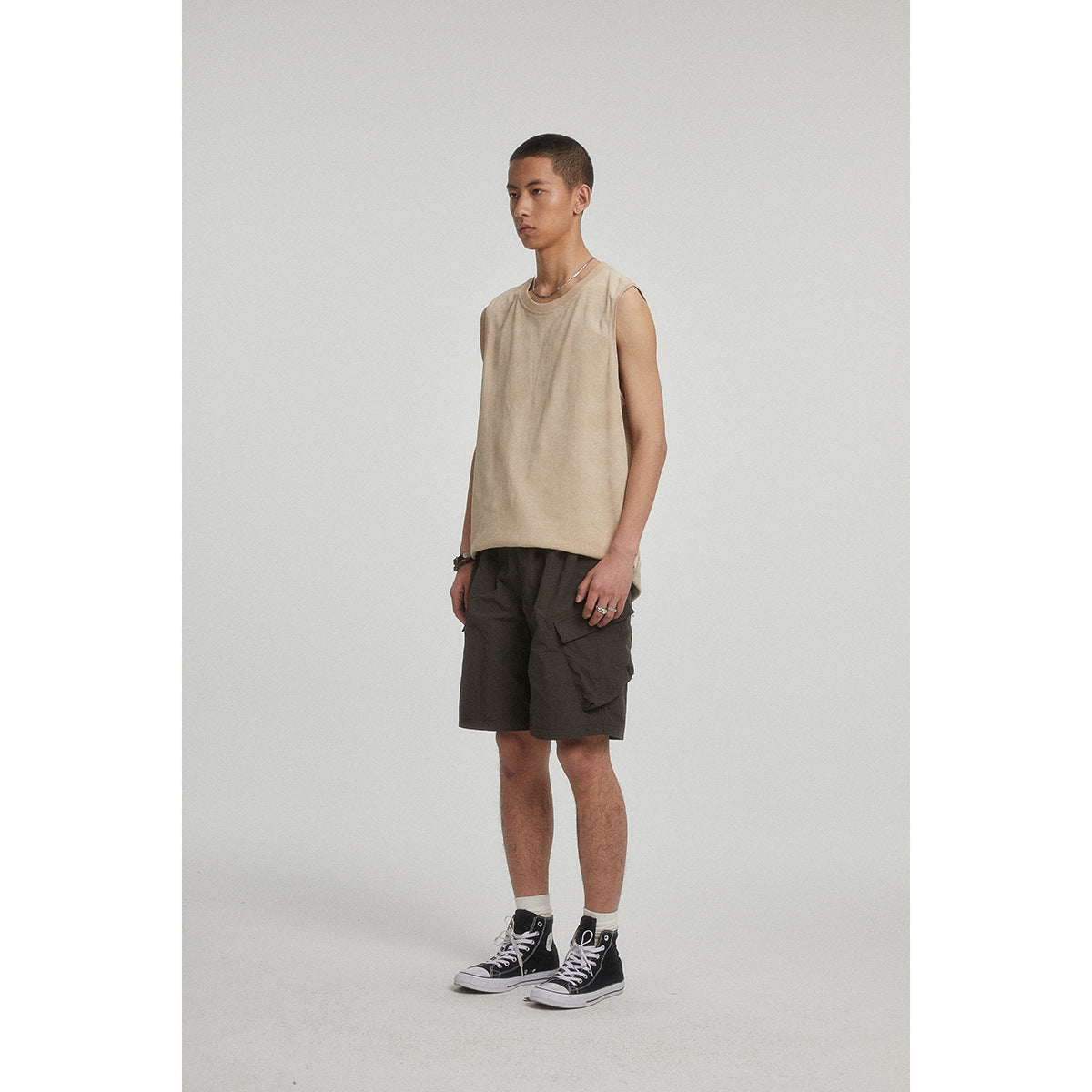Model wearing a beige sleeveless crew-neck top with dark cargo shorts.