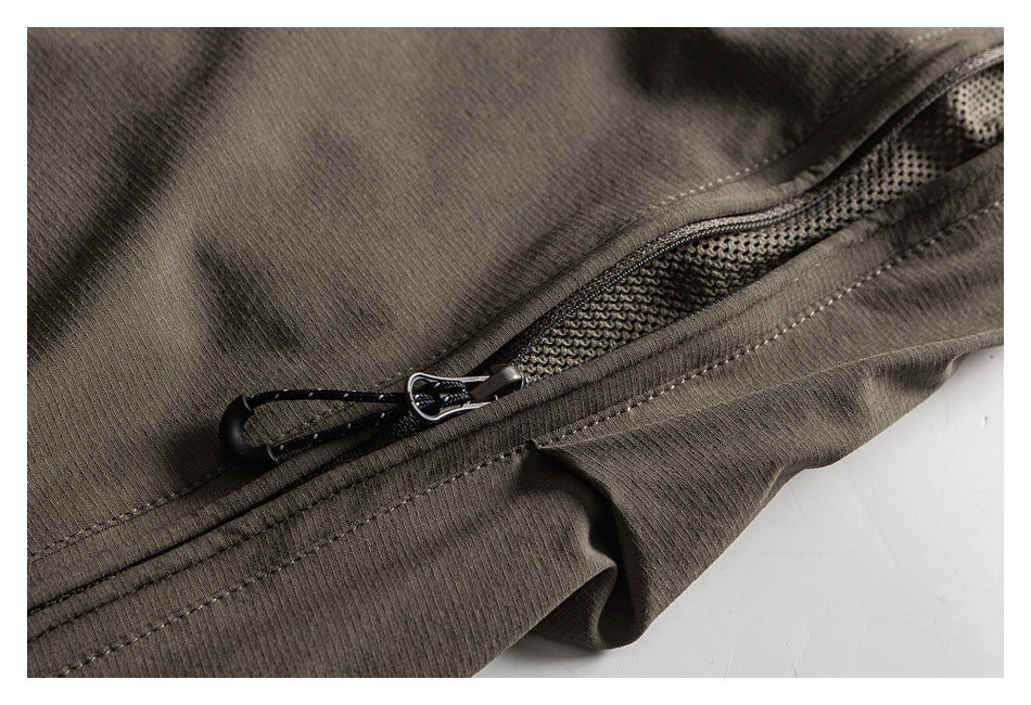 Angled close-up of an olive-gray garment zipper, black cord pull, and textured mesh beneath the opening.
