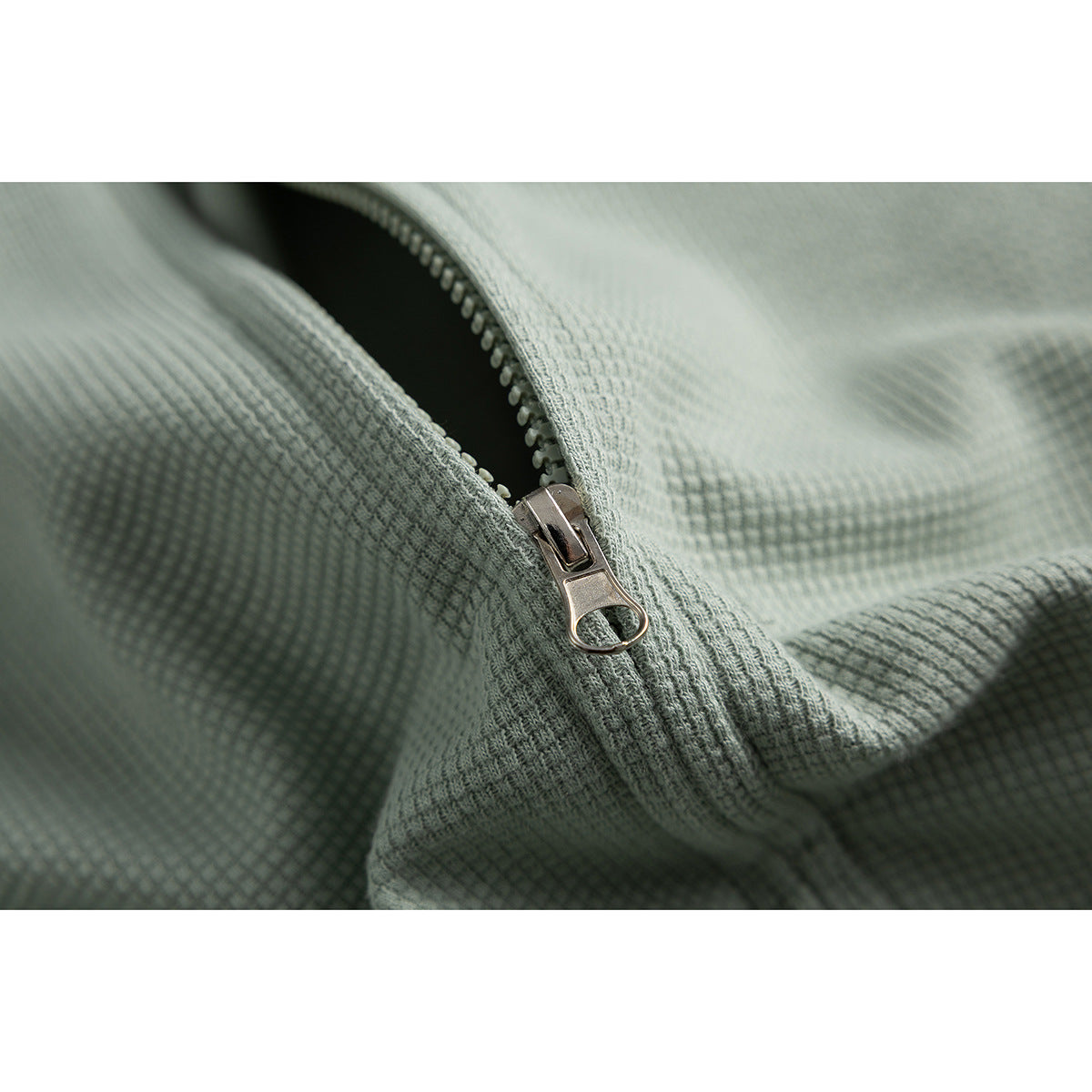 Close-up of the silver zipper and waffle-textured sage-green fabric.