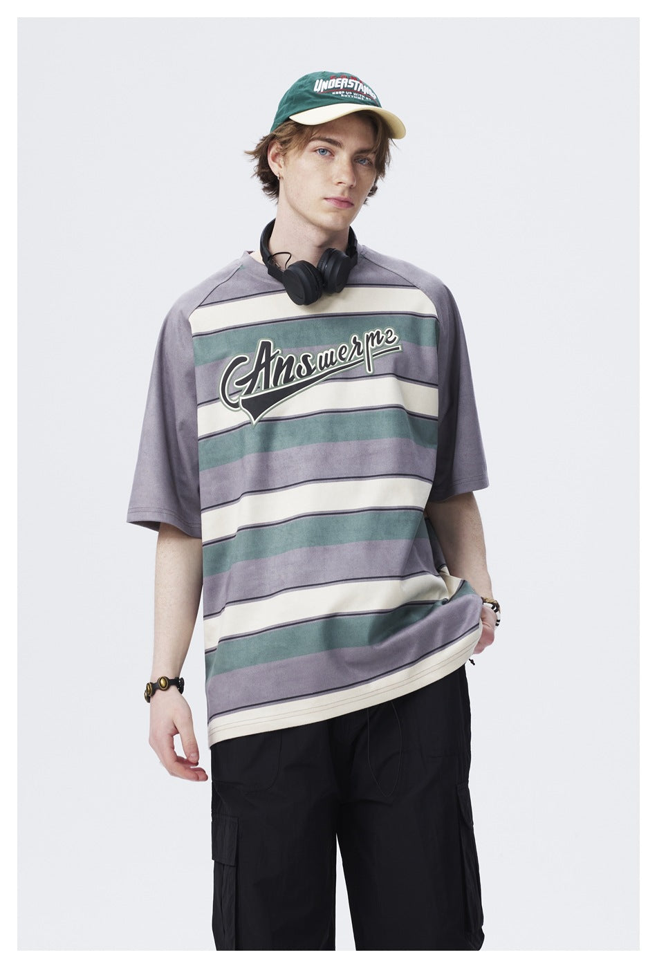 Model wearing a gray, teal, and cream striped oversized T-shirt with large chest lettering; upper body shown.