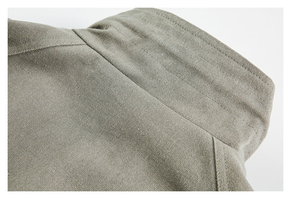 Close-up of gray-khaki garment fabric showing a curved seam and stitched panel construction.