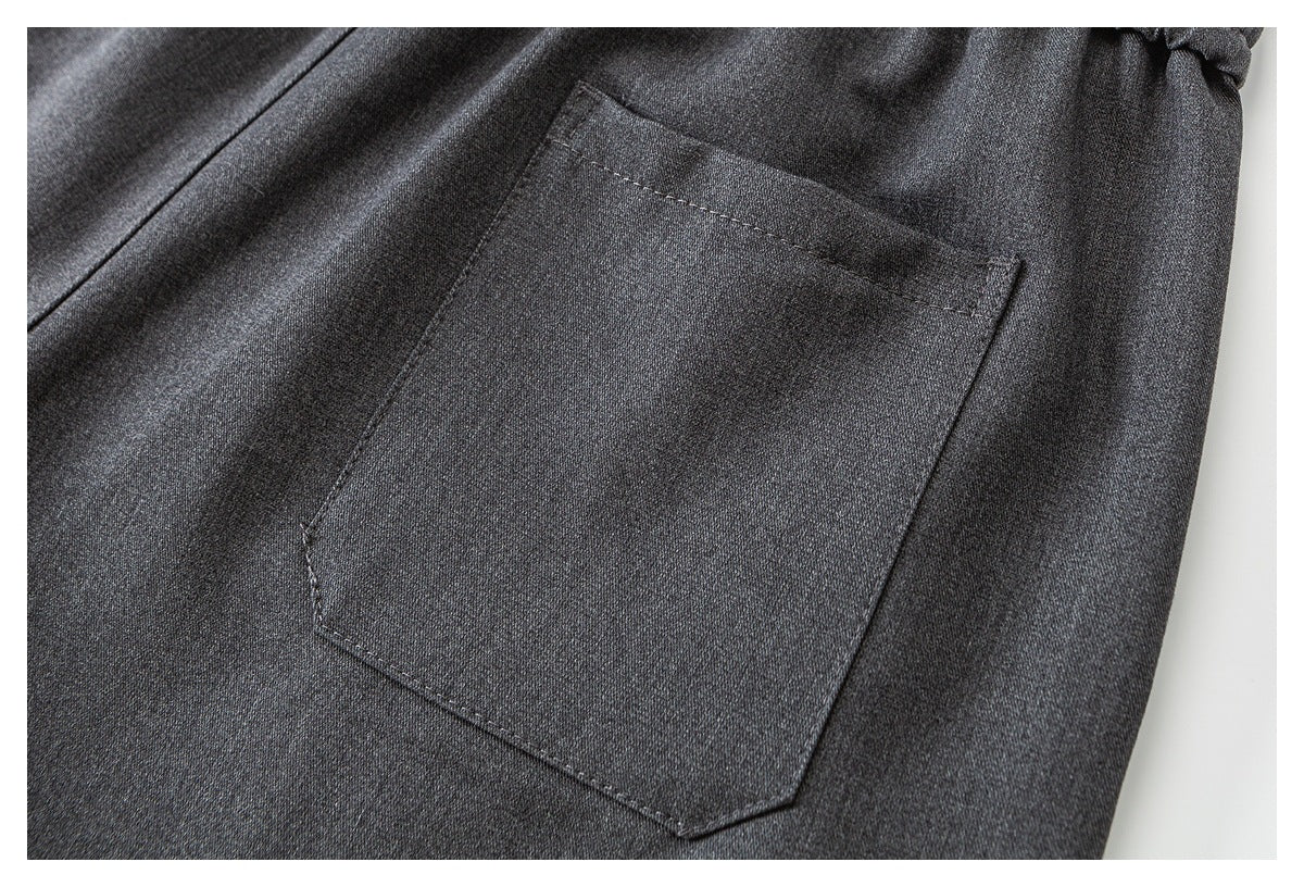 Close-up of a stitched patch pocket on charcoal gray pants.