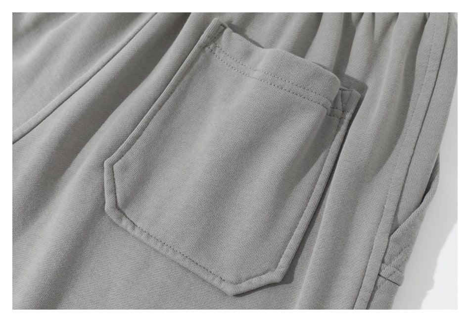 Close-up of a stitched patch pocket on gray sweatpants.