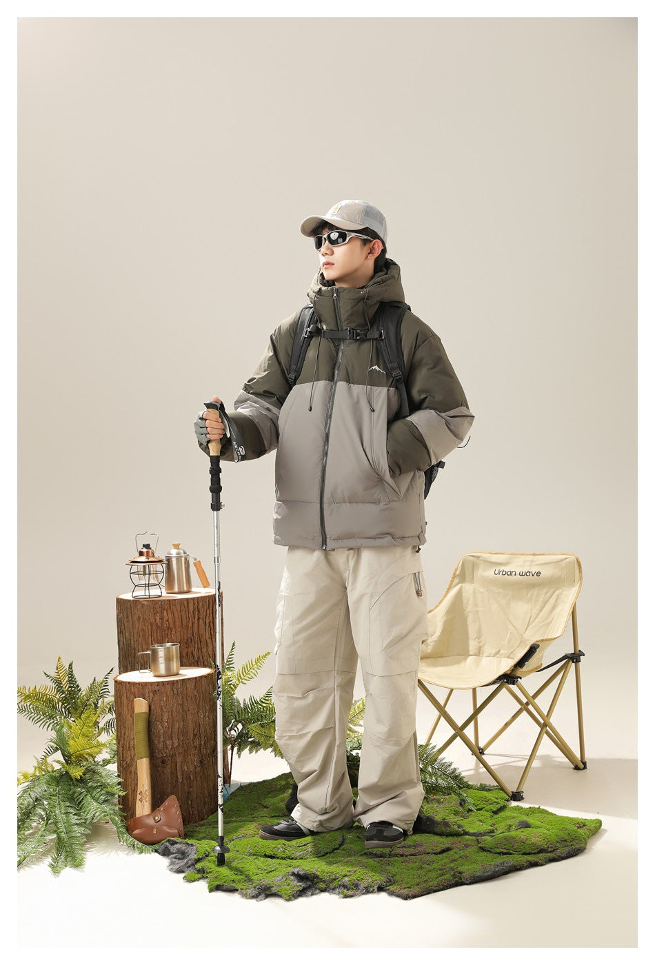 Model wearing an olive and gray color-block hooded puffer jacket with light beige cargo pants.