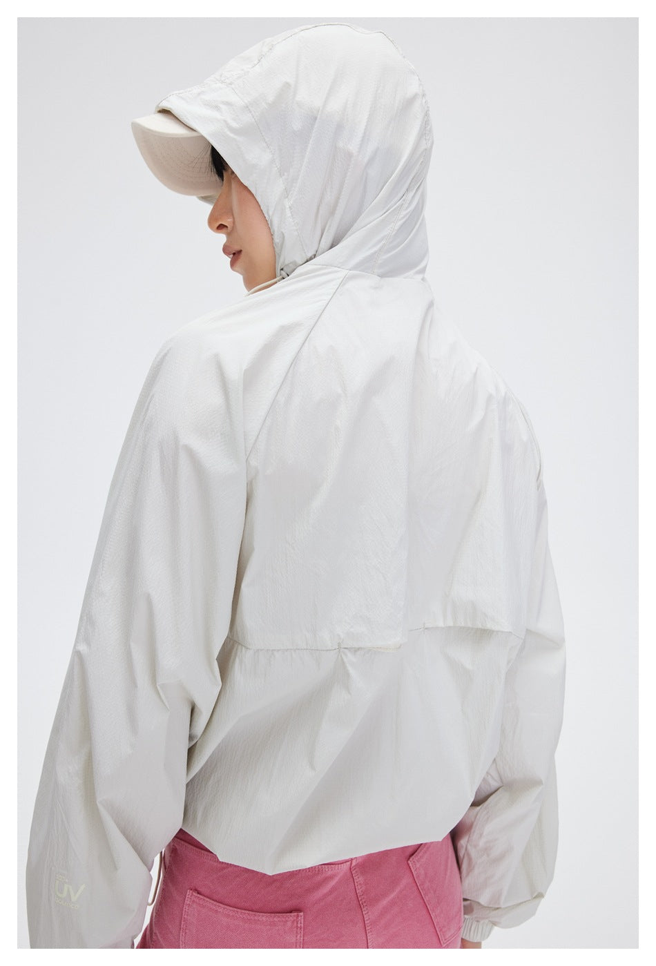 Rear view of a model wearing a white hooded jacket with pink shorts.