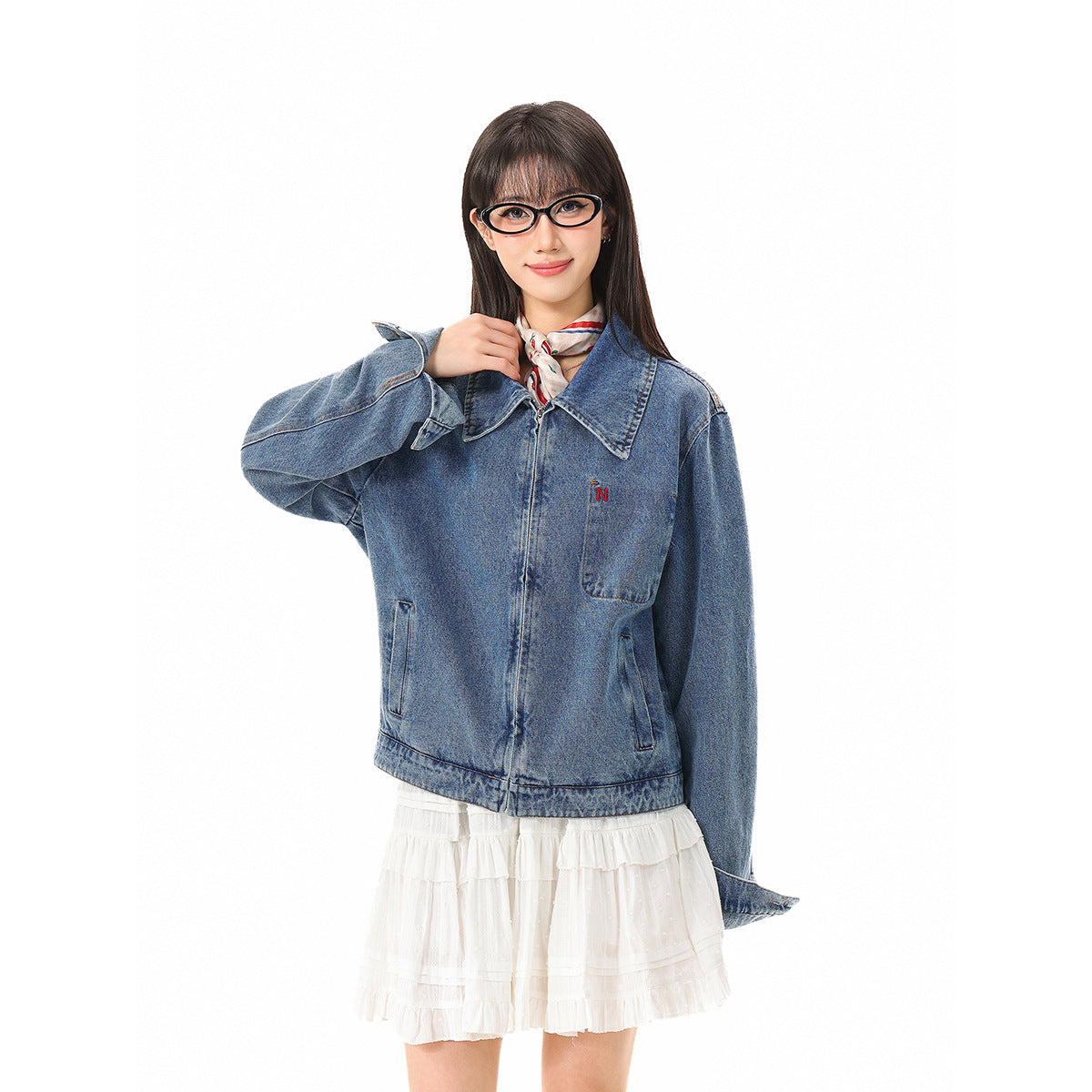 Model wearing a blue denim jacket with a large collar and chest pocket over a white ruffled dress.