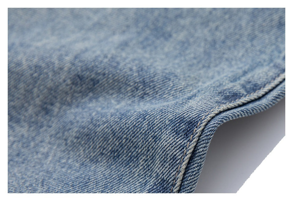 Close-up of faded light-blue denim with a curved, double-stitched seam and finished edge.