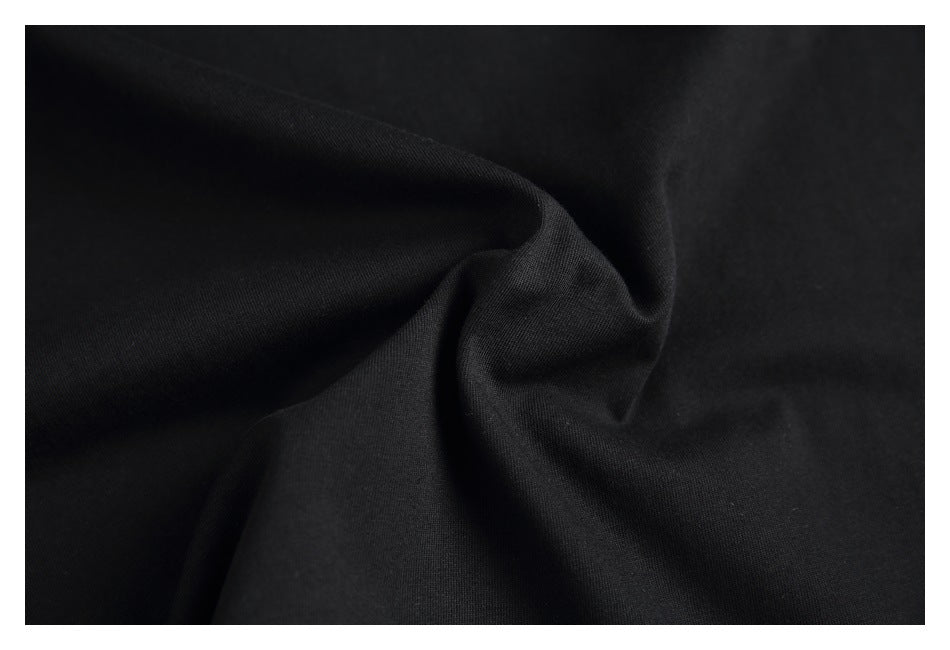 Close-up of black fabric gathered into folds, showing its surface texture.