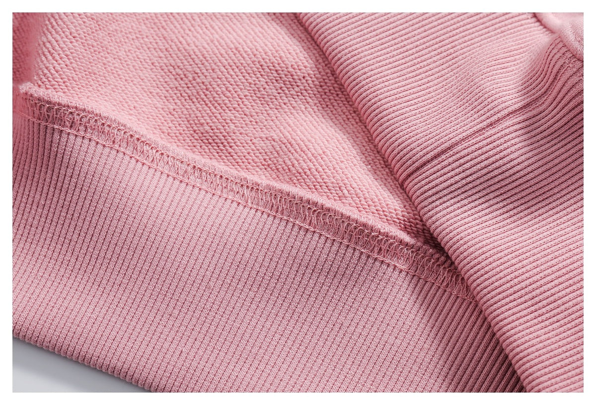 Inside close-up of a pink sweatshirt showing an overlocked seam and ribbed cuff.