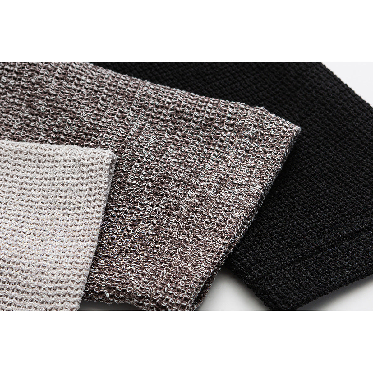 Close-up of three knit fabric colorways in cream, brown, and black.