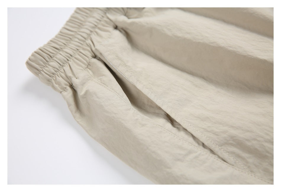Close-up of a light beige garment with a gathered elastic edge and stitched seams.