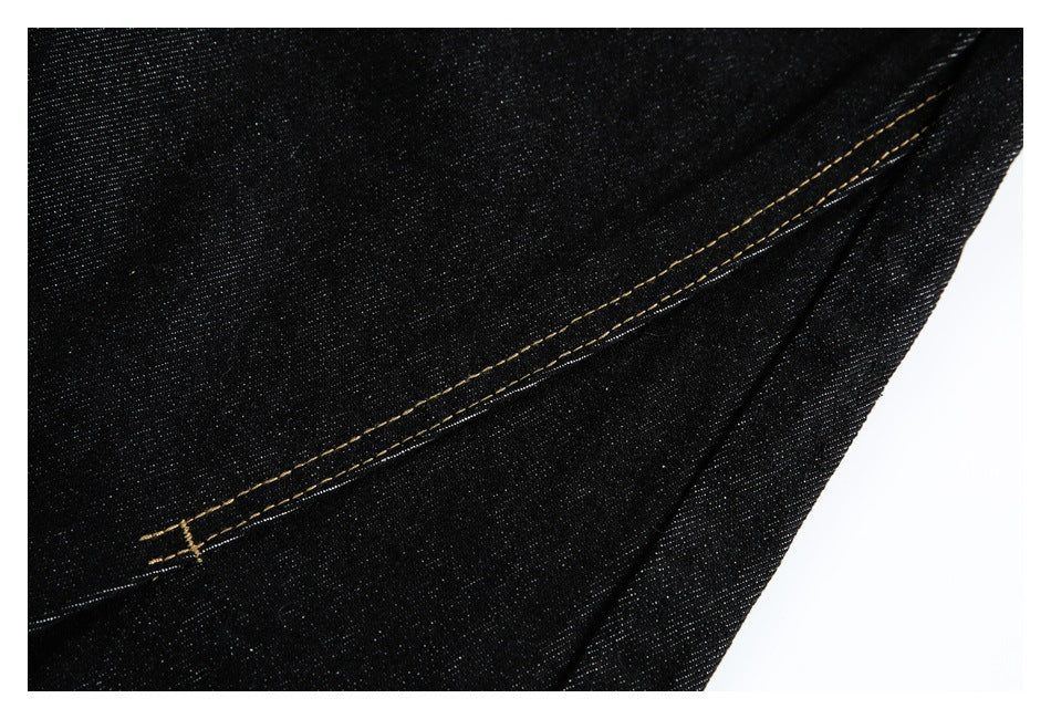 Close-up of a long gold-stitched seam on black denim.