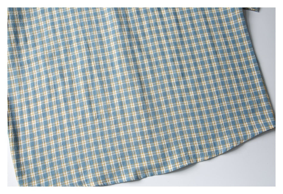 Close-up of the blue, white, and mustard plaid shirt body and stitched lower hem.