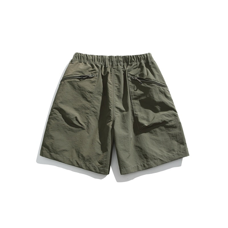 Olive green shorts laid flat, with an elastic waistband and two slanted zip pockets.