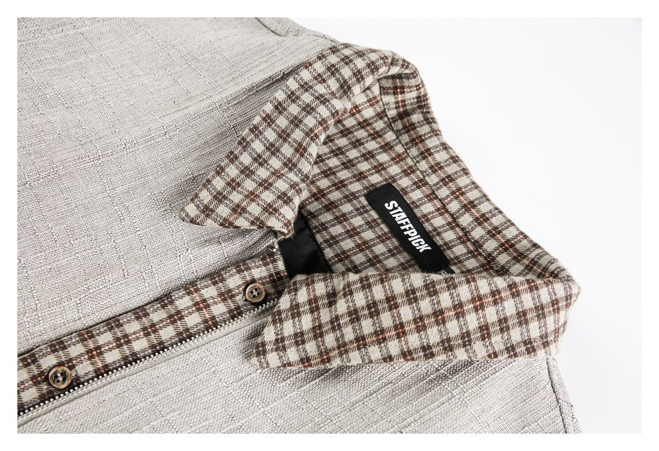 Close-up of a cream garment's brown plaid collar, zipper and buttons, with a black neck label.