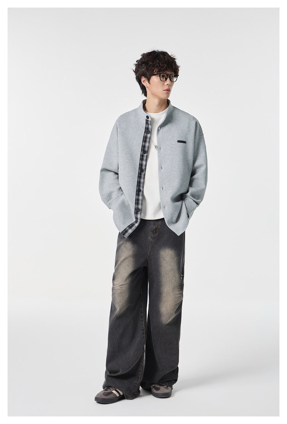 Full-length model wearing a light gray plaid-trim jacket, white top, and oversized dark jeans.