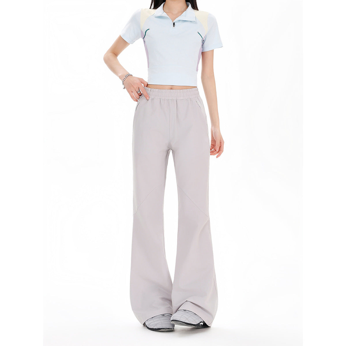 Front view of a model wearing light gray wide-leg pants with an elastic waist and curved seam panels.