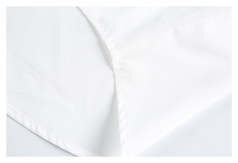 Close-up of white garment fabric showing intersecting stitched seams and a folded hem.