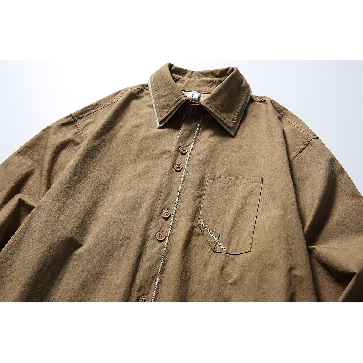Close-up of a brown long-sleeve button-up shirt with a pointed collar, chest pocket, and contrast stitching.
