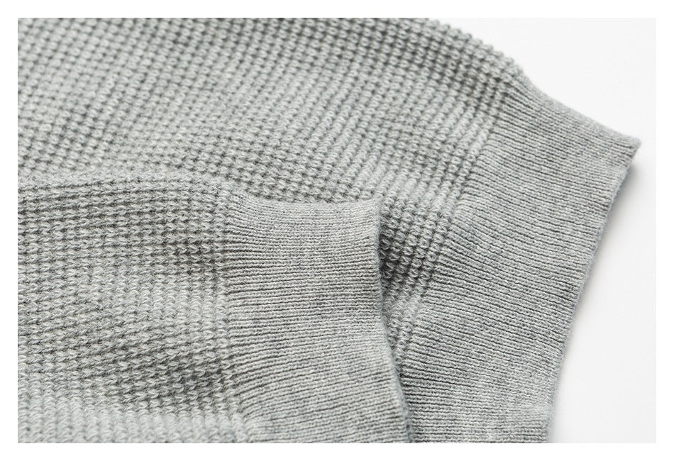 Close-up of the light gray sweater’s textured knit and ribbed sleeve cuff.