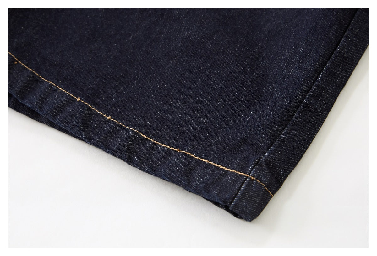 Close-up of a dark indigo denim hem with tan contrast stitching.