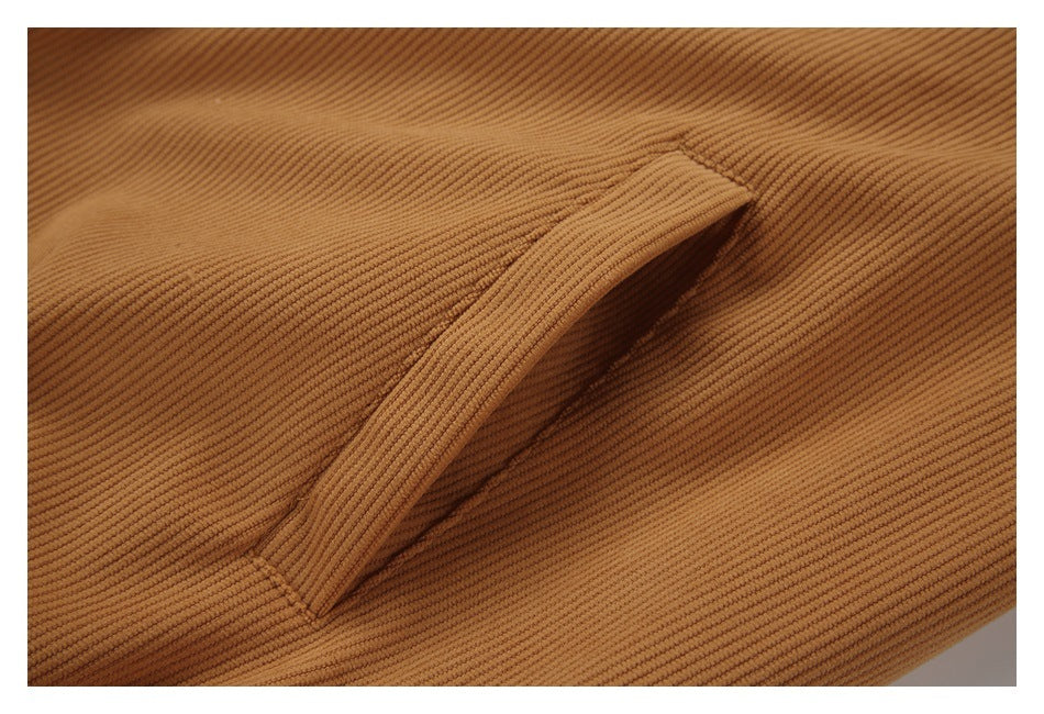 Close-up of a slanted welt pocket on tan ribbed fabric.