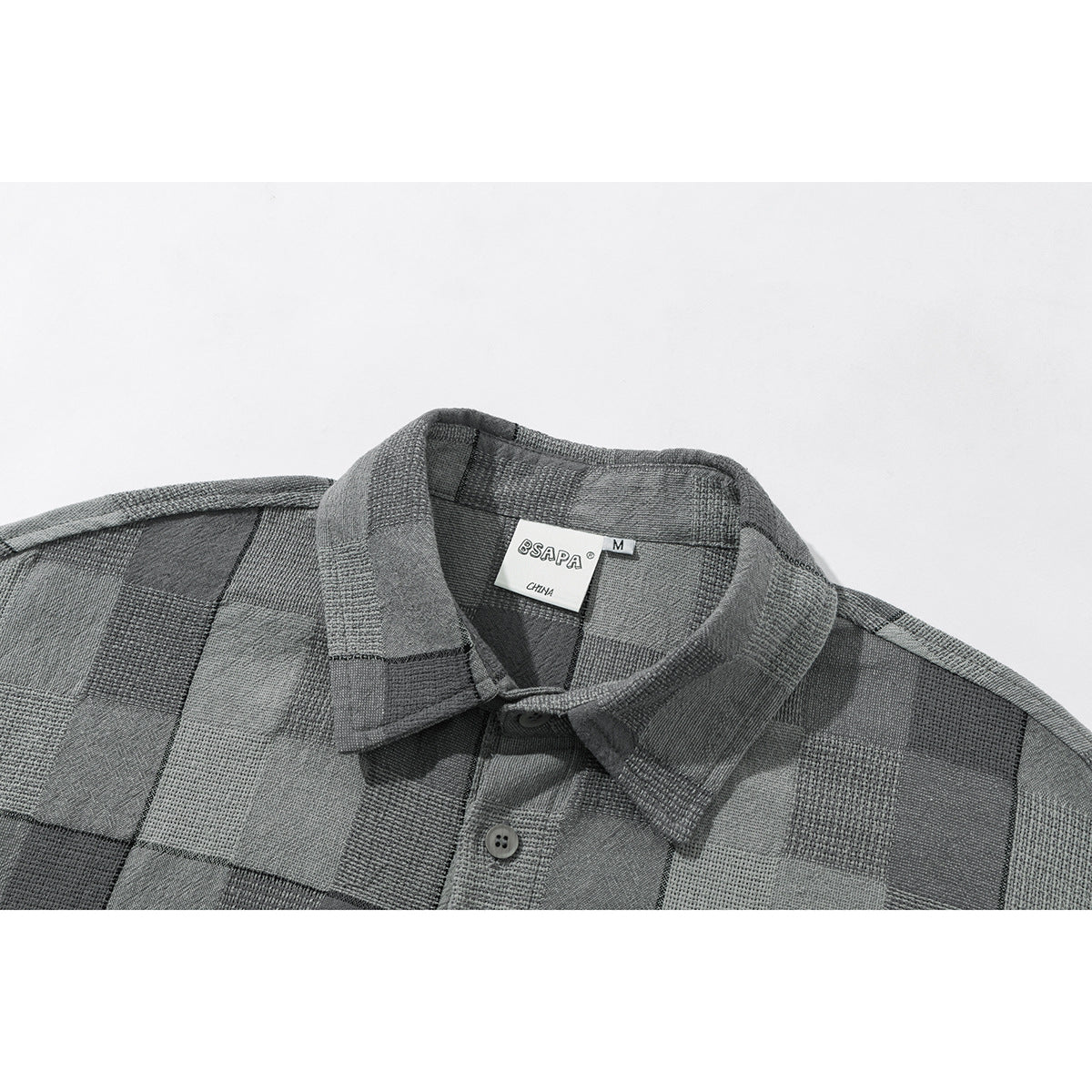 Close-up of a gray checked shirt collar, placket, buttons, and sewn neck label.