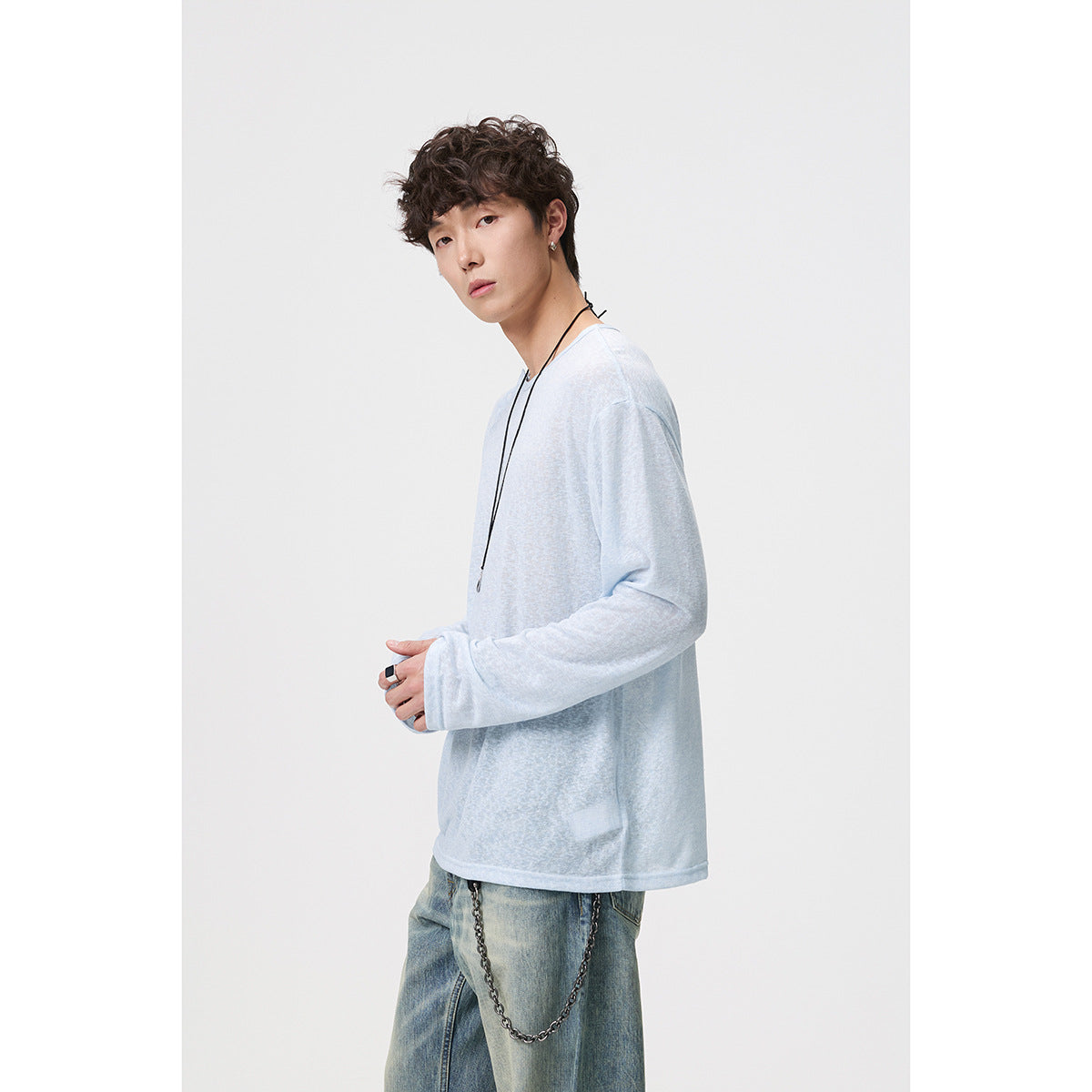 Side view of a model wearing a loose pale blue long-sleeve shirt with a crew neckline.