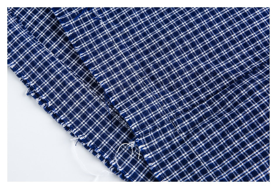 Close-up of navy and white plaid fabric showing a stitched seam and frayed edge.