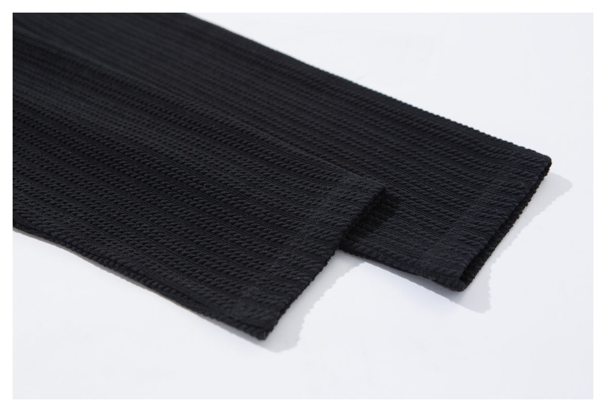 Close-up of two finished edges on a black textured knit garment.