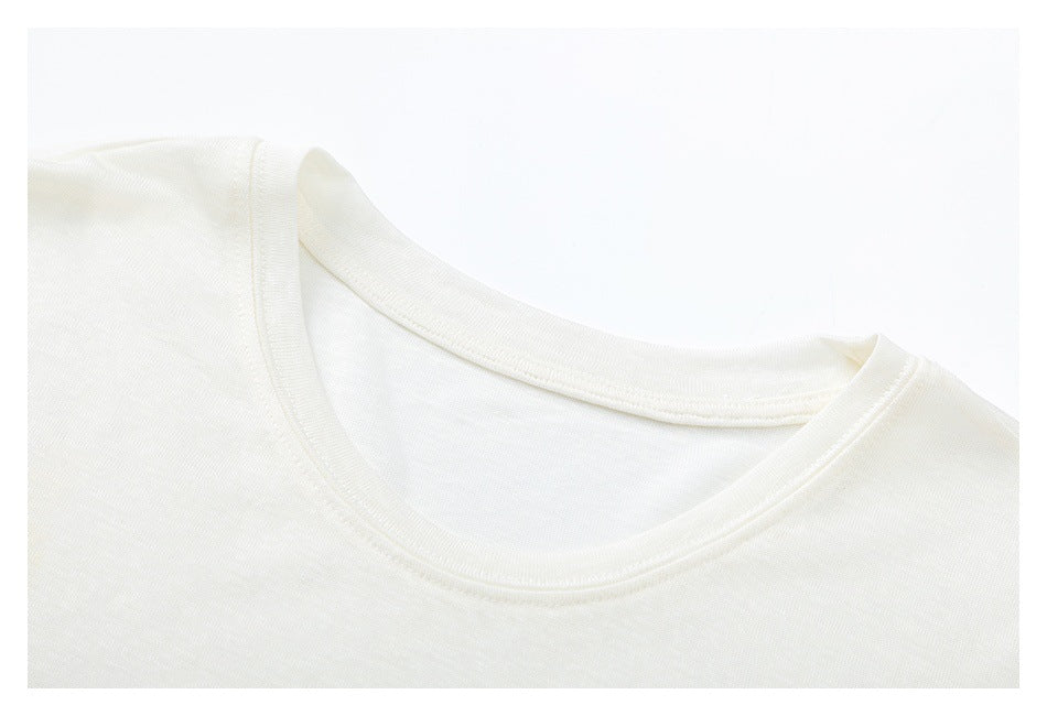 Close-up of an ivory T-shirt's crew neckline and shoulder seam.
