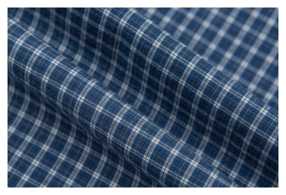 Macro view of blue, white, and brown plaid shirt fabric draped in a fold.