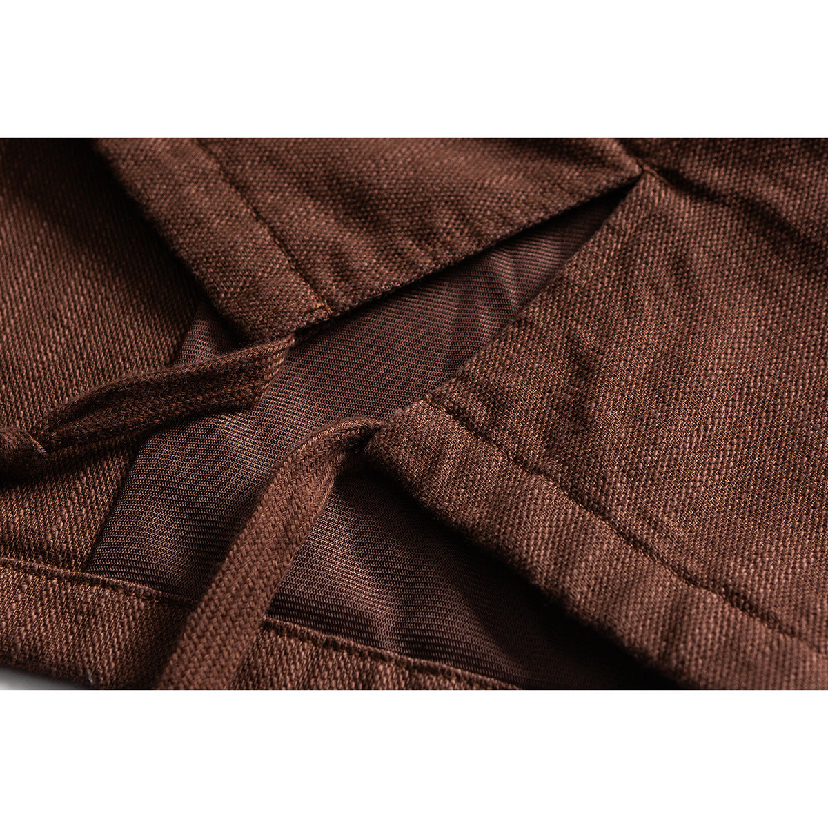 Close-up of rust-brown jacket fabric, seams, and an inner mesh panel.