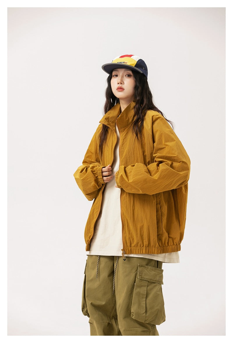 Model wearing a mustard-gold oversized zip jacket with a raised collar and elastic hem.