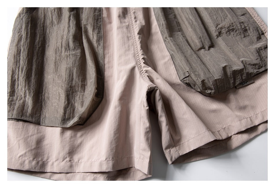 Close-up of the shorts’ layered leg hems, showing pale beige fabric beneath crinkled gray panels.