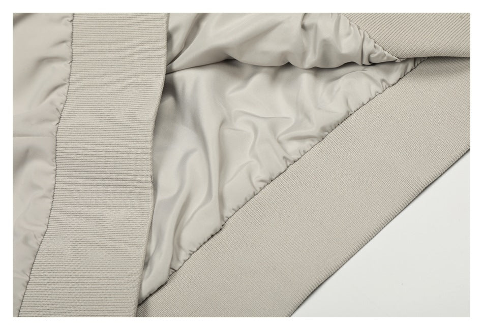 Close-up of the ivory jacket's smooth inner lining and wide ribbed knit hem trim.