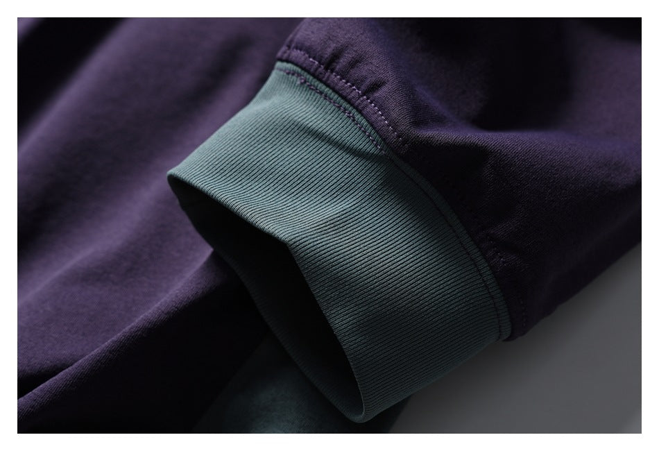 Close-up of a muted teal ribbed cuff on the purple sweatshirt sleeve.