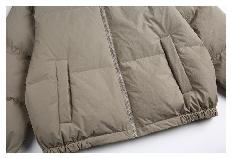 Close-up of the taupe jacket's lower front, showing two pockets, center zipper, and gathered hem.