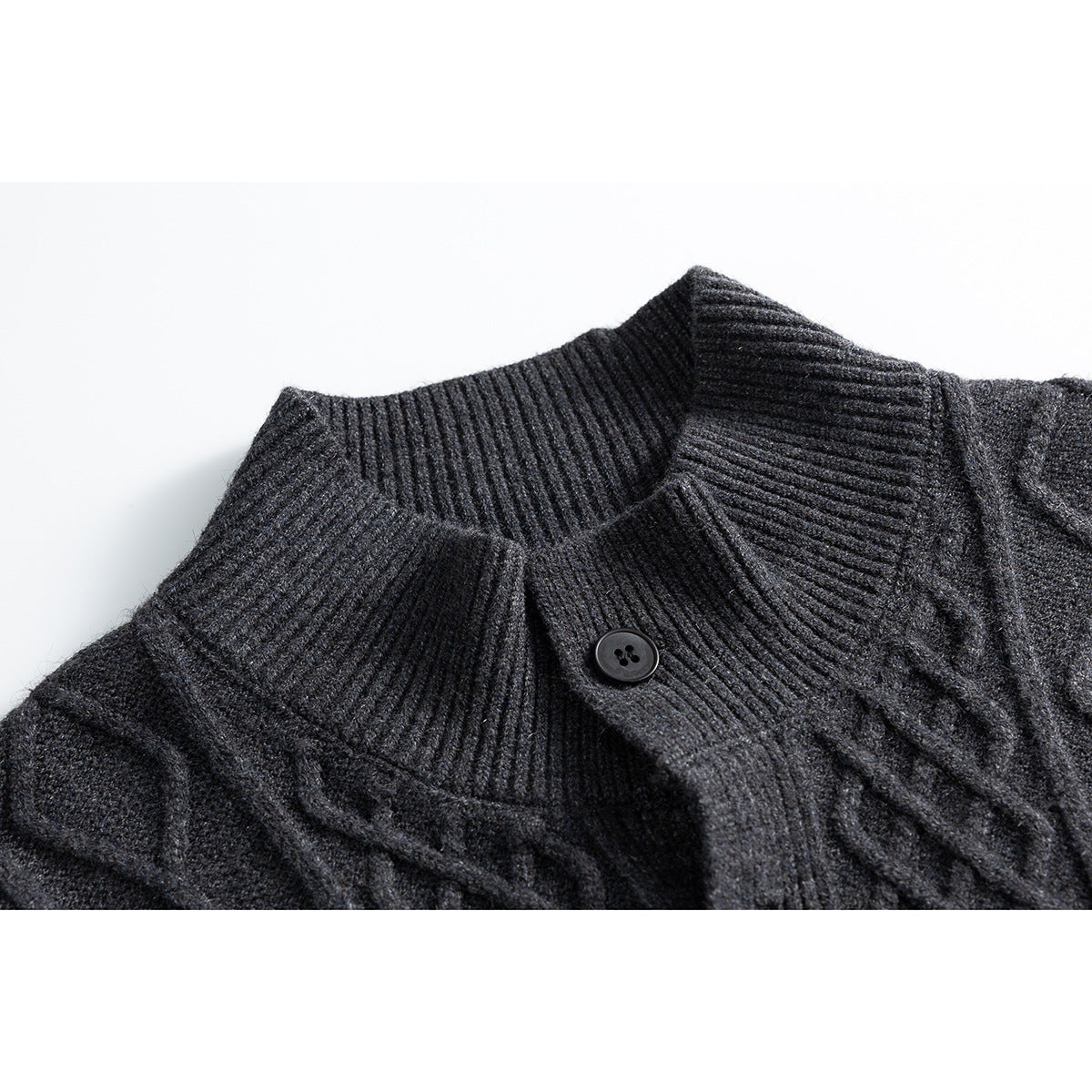 Close-up of a charcoal cable-knit cardigan's ribbed stand collar and dark button.