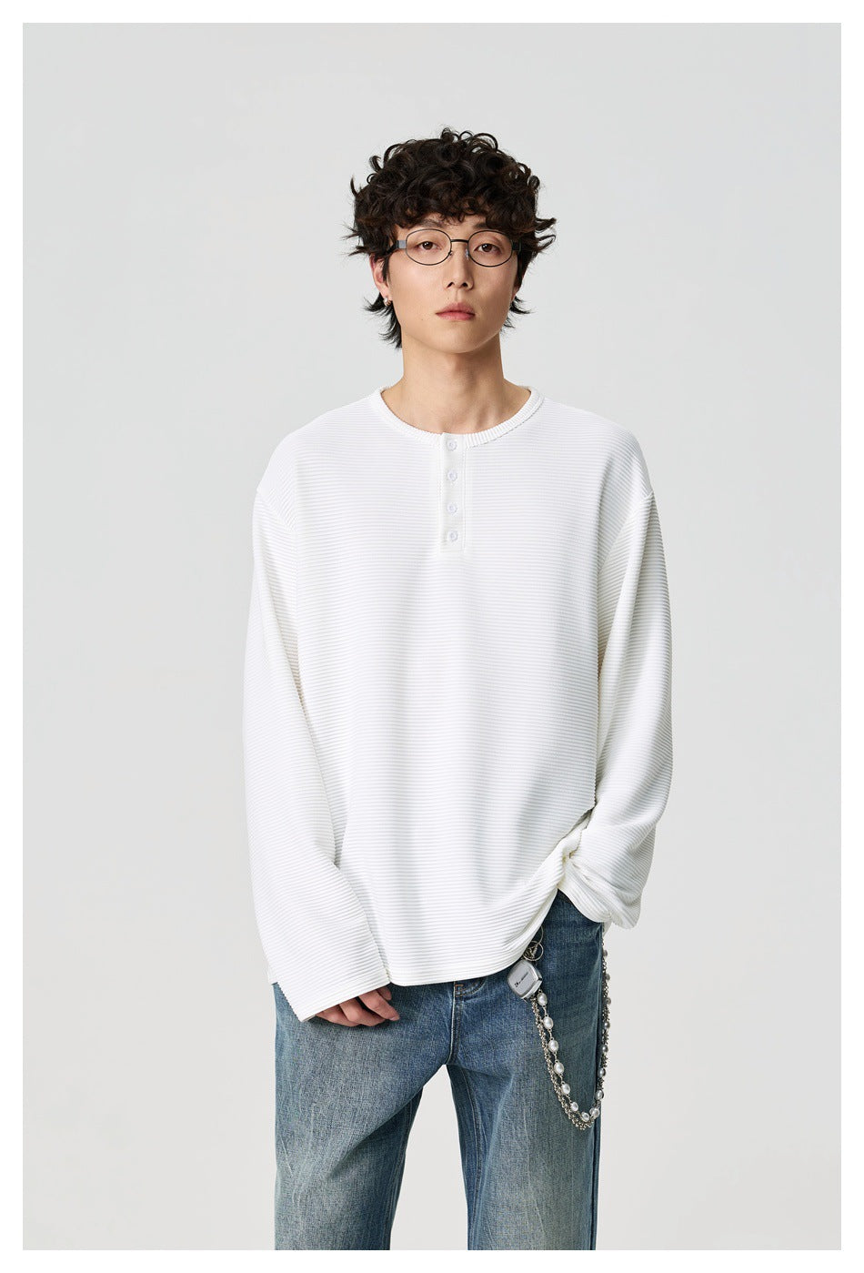 Model wearing a white ribbed long-sleeve henley shirt, shown from the front with the button placket visible.