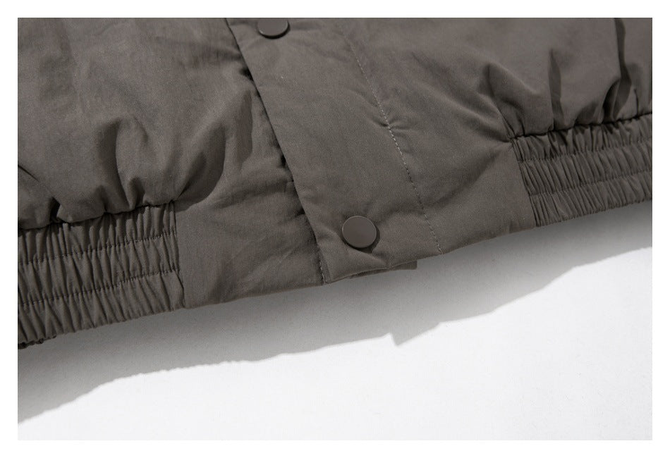 Close-up of a dark gray-brown garment with snap buttons and gathered elastic along the hem.