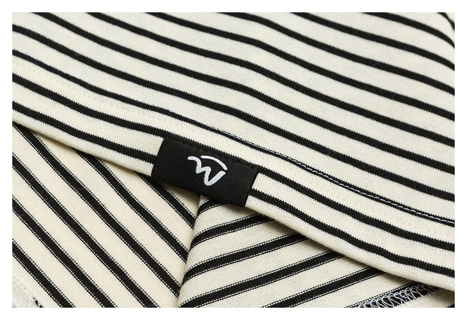 Close-up of a black-and-cream striped garment with a small black sewn-in label bearing a white symbol.
