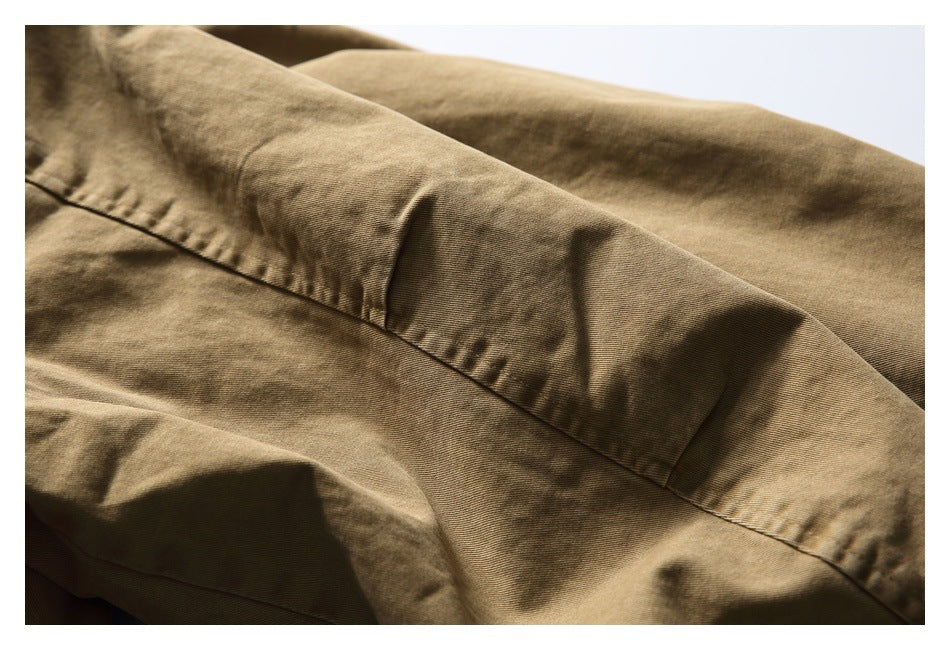 Close-up of a tan-brown garment showing a curved stitched seam and folded fabric panels.