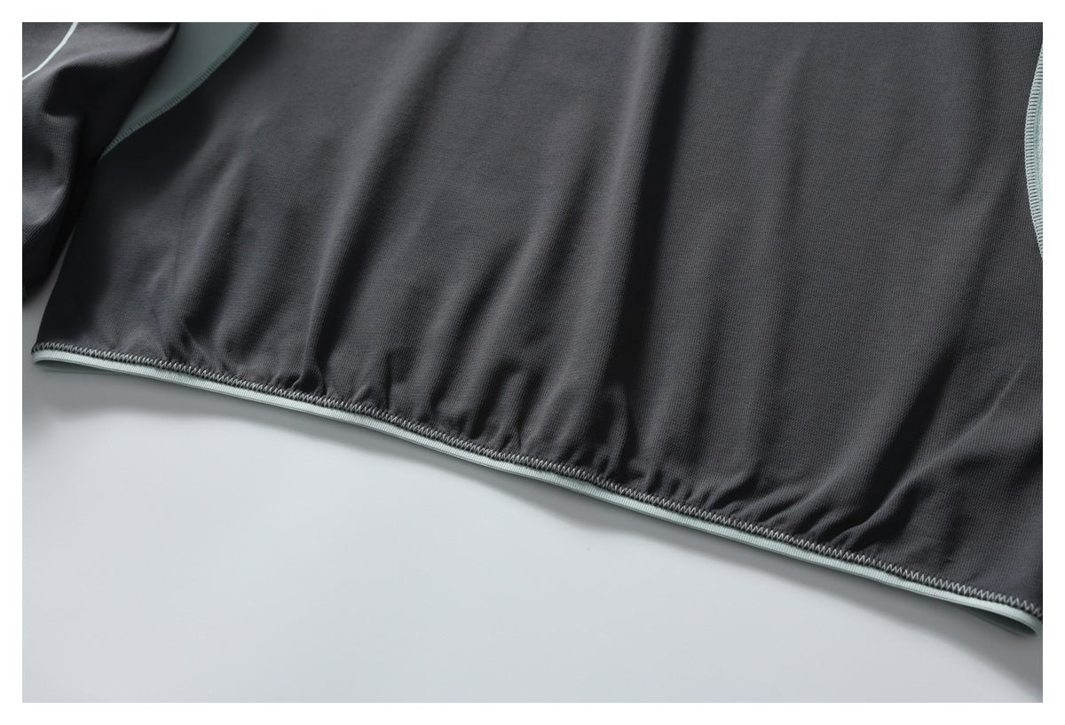 Close-up of a dark gray garment hem with pale mint trim and stitching.