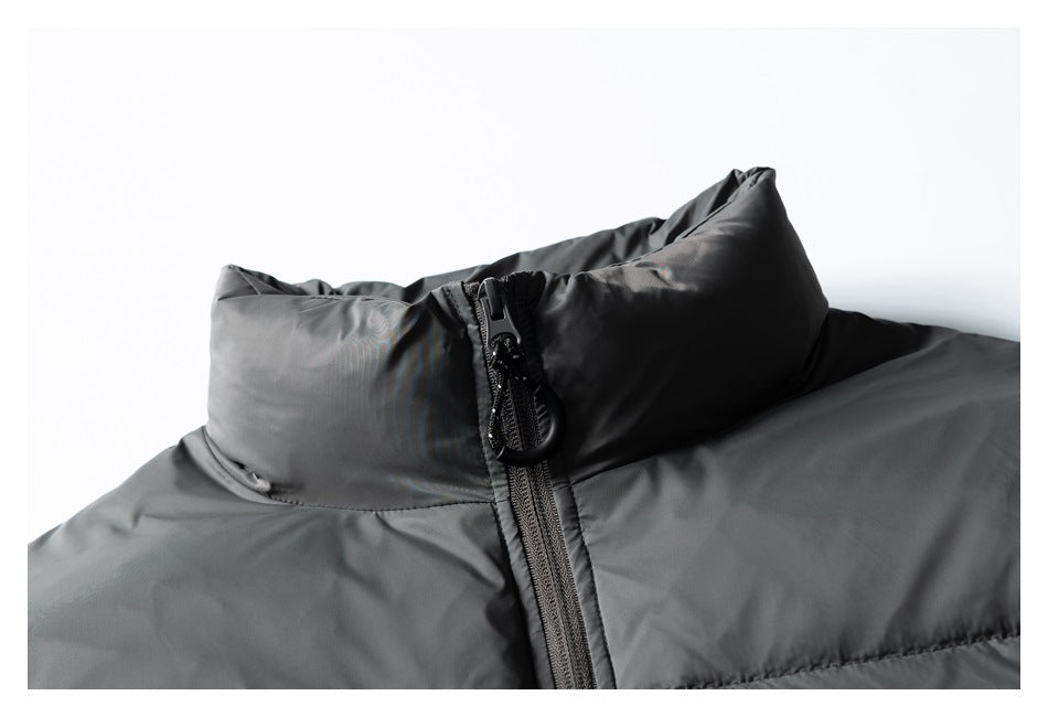 Close-up of a charcoal puffer jacket's raised collar and front zipper with a large pull tab.