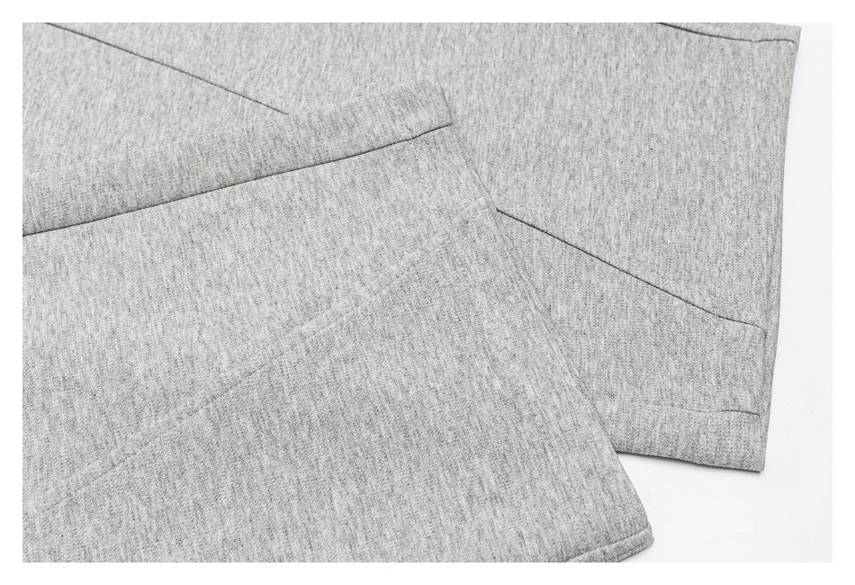 Close-up of heather-gray pants fabric, showing seams and a finished hem.