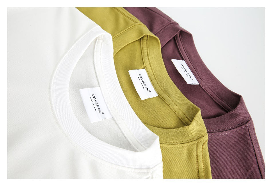Close-up of white, mustard-yellow, and burgundy T-shirt collars with sewn-in ANSWER ME labels.